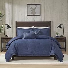 a bed with blue comforter and pillows in a room next to two nightstands