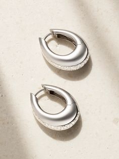 Designer Ananya Malhotra’s Indian heritage and spiritual upbringing inspire ANANYA's striking pieces. Cast from 18-karat white gold, these 'Chakra Icon' hoop earrings are defined by a sleek, chunky profile traced by a channel of round-cut diamonds. Pair yours with the matching bracelet in our edit. Classic Diamond Jewelry With Shiny Finish, Luxury Silver Huggie Earrings With Polished Finish, Modern White Gold Huggie Earrings With Diamond Accents, Luxury Teardrop Earrings With Pave Setting, Modern White Gold Huggie Earrings, Modern Silver Huggie Earrings For Anniversary, Luxury White Hoop Earrings For Evening, Luxury Sterling Silver Jewelry With Halo Design, Luxury Oval Earrings With Shiny Finish