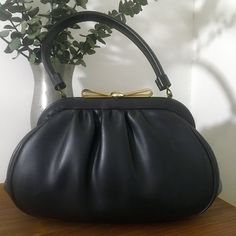 "1960s Granada USA Black Soft Vinyl Leather Top Handle Handbag, Vintage 60s Purse Classy 1960s Granada USA black soft vinyl leather top handle handbag that features: Gold tone metal hardware with a really pretty gold tone metal bow clasp closure that works well and closes tightly. Opens to a black satin lining with one interior side open pocket and one interior side metal zippered pocket. Stamped Granada USA There are protective feet on the bottom of the bag. Nearest mint condition *the exterior Mid-century Style Leather Evening Bag, Mid-century Leather Evening Bag, Evening Satchel With Rolled Handles, Evening Satchel With Rolled Top Handles, Formal Shoulder Satchel With Rolled Handles, Elegant Evening Shoulder Bag With Rolled Handles, Elegant Shoulder Bag With Rolled Handles For Evening, Evening Satchel Bag With Rolled Handles, Retro Leather Bag With Detachable Handle