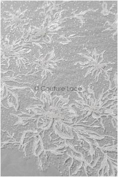 an embroidered lace with white flowers and leaves on grey fabric, as well as the words couture lace