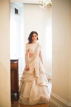 a woman in a white dress standing next to a window