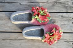 two slippers with red flowers on them sitting on a wooden floor next to a pair of shoes