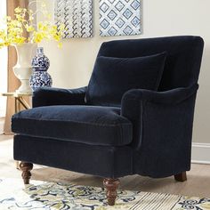 a blue chair sitting on top of a rug next to a vase filled with flowers