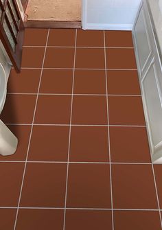 an overhead view of a bathroom with brown tile flooring and white toilet in the corner