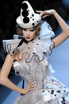 a woman wearing a white hat and dress with black polka dots on it's head