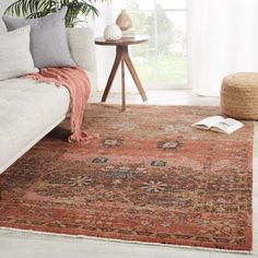 a living room area with a couch, rug and coffee table in front of a window