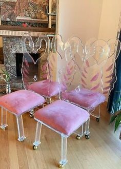 two pink chairs sitting next to each other in front of a fire place on a hard wood floor