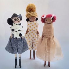 three dolls are dressed in different clothes and hats, one is wearing a polka dot dress