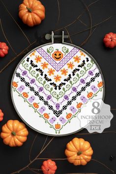 a cross stitch pattern with pumpkins and flowers in the background on a black surface