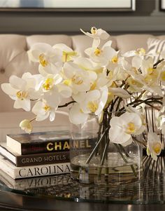 a glass table topped with white flowers and books