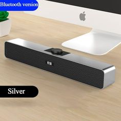 the bluetooth version of the silver speaker is shown next to an apple monitor and keyboard