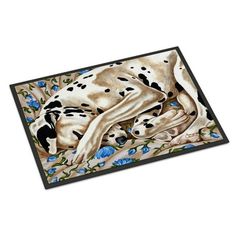 a dalmatian dog laying on top of a blue flower covered floor mat in front of a white background