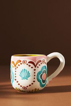 a coffee cup sitting on top of a table next to a brown wall and floor