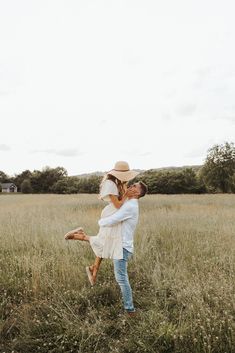 a man holding a woman in the middle of a field