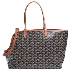 a brown and black handbag with an orange handle on the bottom, in front of a white background