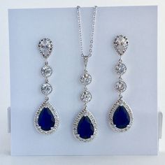 I've created this absolutely gorgeous long luxury blue sapphire cubic zirconia bridal set in rhodium plated brass setting. This set includes: #Earrings feature a large teardrop with pear cut blue sapphire cubic zirconia center surrounded by tiny round zirconia crystals. Teardrop dangles from a bright cubic zirconia ear stud and two round cubic zirconia connectors. Total length of the earring is 6 cms. #Necklace pendant features a large teardrop with pear cut blue sapphire cubic zirconia center s Teardrop Sapphire-colored Cubic Zirconia Jewelry, Teardrop Sapphire Cubic Zirconia Jewelry, Sapphire Cubic Zirconia Dangle Jewelry, Sapphire Jewelry Sets For Wedding, Sapphire Cubic Zirconia Wedding Jewelry, Sapphire Cubic Zirconia Jewelry For Wedding, Sapphire Color Drop Cubic Zirconia Jewelry, Sapphire Jewelry With Sparkling Stones For Wedding, Elegant Silver Sapphire Jewelry Sets