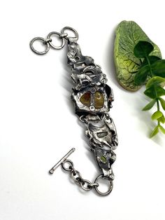 "Artisan Amber gemstone bracelet Hand-made Sterling Silver 925 Stones used: Baltic Amber, Abalone Shell, Pearls, Peridot, Amethyst Amber stone -Height - 30mm (with bail), Width - 22mm Length - 8 1/2 inches, good for 7 and 7 1/2 inches Heigh of bracelet - 1 3/8\" Unique Handcrafted One-of a-kind Design Bracelet Each Piece of Jewelry in my Collection is Absolutely One of a Kind! When you start wearing a piece of my jewelry you will fall in love with it more and more each day and feel that good Ene Brutalist Pendant Jewelry Gift, Sterling Silver Gemstone Fusion Bracelets, Sterling Silver Fusion Bracelets With Gemstones, Sterling Silver Fusion Bracelet With Gemstones, Artisan Hand Forged Bangle Jewelry, Unique Hand Forged Bangle Jewelry, Handmade Metal Fusion Bracelets, Unique Metal Chain Bracelet For Gift, Hand Cast Brutalist Metal Jewelry