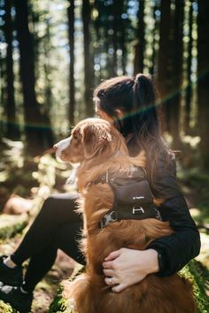 a woman sitting in the woods with her dog