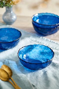 three blue bowls and two gold spoons on a table