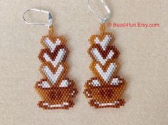 two brown and white beaded earrings with hearts on them sitting on top of a table