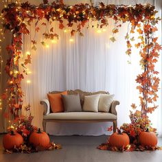 a couch and some pumpkins in front of a white curtain with lights on it