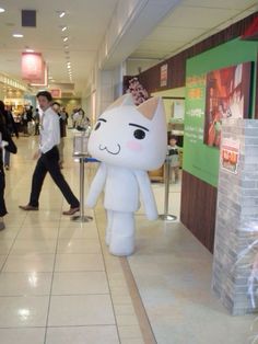 an inflatable unicorn is walking down the hall with other people behind it and onlookers