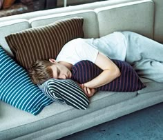 a young boy sleeping on a couch with pillows