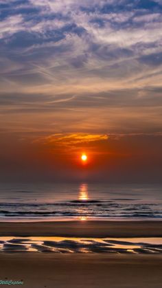 the sun is setting over the ocean with clouds in the sky