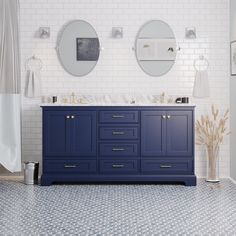 a bathroom with blue cabinets and two round mirrors on the wall above them is shown