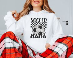 a woman sitting on the floor with her legs crossed wearing pajamas and a hoodie that says soccer mama