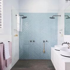 a bathroom with blue and white tiles on the walls, two sinks and a shower