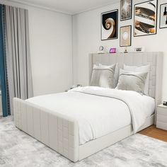 a white bed sitting in a bedroom next to two pictures on the wall above it