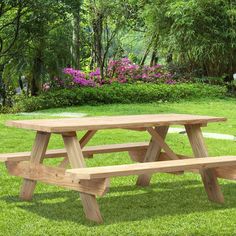 a wooden picnic table sitting on top of a lush green field