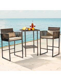 an outdoor table with two chairs next to the ocean