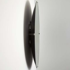 a mirror mounted to the side of a white wall next to a black and silver clock