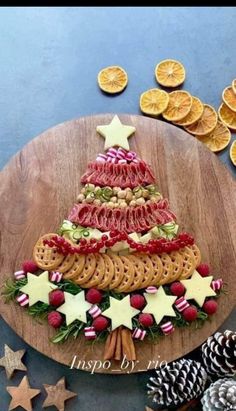 a christmas tree made out of pretzels on a wooden platter surrounded by orange slices