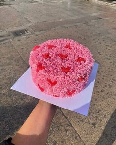 a pink cake sitting on top of a piece of paper next to a parking lot