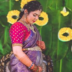 a woman in a purple sari is standing near flowers