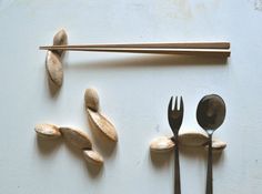 spoons, forks and beans are arranged on a white surface with chopsticks