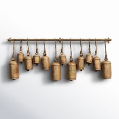 an assortment of bells hanging from a wooden rack on a wall in front of a white background