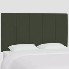 an upholstered headboard with white sheets and pillows