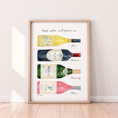 three bottles of wine are displayed in a wooden frame on the floor next to a white wall