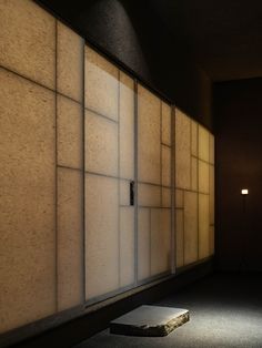 a dimly lit room with an open door on the wall and a stone bench in front of it