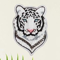 a close up of a white tiger head made out of bead and sequins