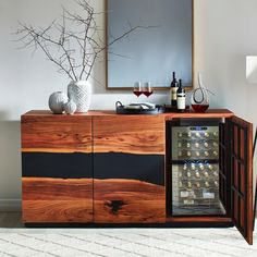 a wooden cabinet with wine glasses and bottles in it next to a mirror on the wall