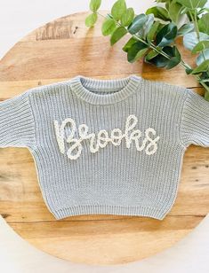 PERSONALIZED BABY, TODDLER & KID'S HAND EMBROIDERED KNIT SWEATER These customizable sweatshirts are such a beautiful piece to share with the littles in your life. They can also be used for pregnancy and birth announcements and, make an amazing baby shower or birthday gift too! ABOUT ME: *The lettering is unique to each sweatshirt and stencilled in the appropriate sizing. Each name is hand-embroidered with a high-quality wool yarn. *All items are hand-embroidered so no two designs are the same! Y Oversized Knit Tops With Letter Print, Playful Knitted Crew Neck Top, Customizable Cute Crew Neck Sweater, Cute Customizable Crew Neck Sweater, Playful Long Sleeve Customizable Tops, Fall Sweater With Name Print And Crew Neck, Fall Crew Neck Sweater With Name Print, Boys Embroidered Sweater, Baby Sweater With Name