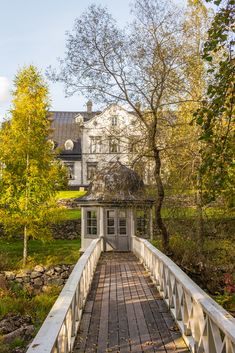 a white house sitting on top of a lush green field next to a forest filled with trees