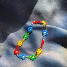 Red/Blue/Yellow/Green daisy chain bracelet with gold clasp. Red Bracelet Gift For Spring, Handmade Red Bracelets For Spring, Multicolor Trendy Bracelet With Flower Charm, Trendy Multicolor Bracelets With Flower Charm, Trendy Multicolor Bracelet With Flower Charm, Red Flower Beaded Bracelet, Handmade Red Flower Bracelet, Blue And Yellow Bracelet, Daisy Chain Bracelet