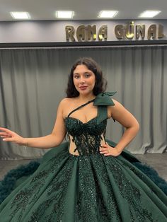 a woman in a green ball gown posing for the camera with her hands out and one hand on her hip