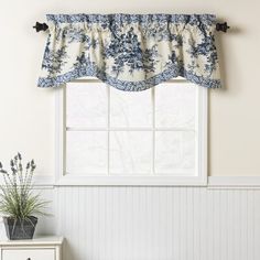 a window with a blue and white flowered valance